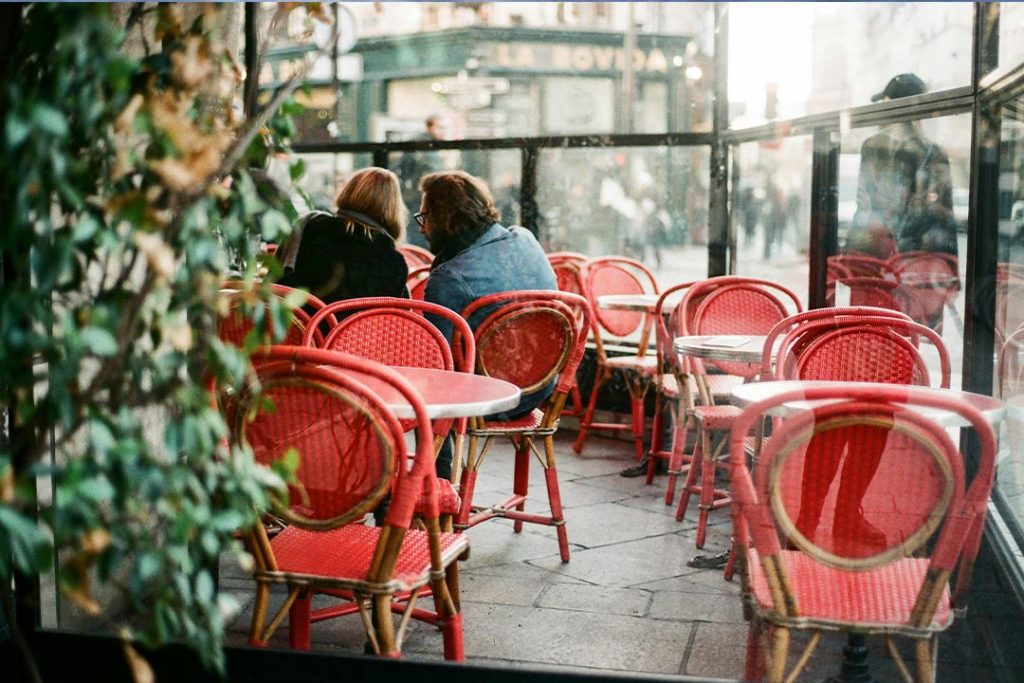 Vista de la calle de un bistró con mesas y sillas. Café parisino Somos Paris